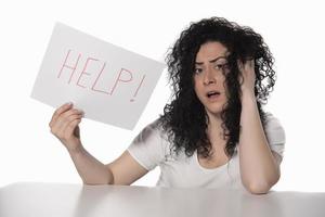 young attractive frustrated and tired businesswoman holding help sign message overworked at office computer, exhausted, sad under pressure and stress isolated on white photo