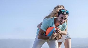 pareja jugando fútbol americano en un caluroso día de verano. sesión de fotos de pareja jugando al rugby