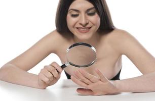 Woman looking her hand nails true magnifying glass photo