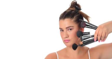 young girl posing with makeup brushes on a white background photo