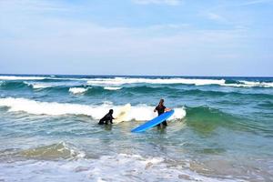 pareja de surfistas esperando las olas altas en la playa - deportistas con tablas de surf en la playa - deporte extremo y concepto de vacaciones foto