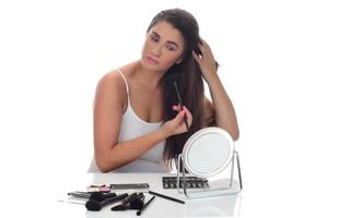 Portrait of a young woman applying make up on her face. Isolated on white background photo