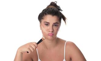 Portrait of a young woman applying make up on her face. Isolated on white background photo