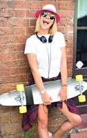 Beautiful hipster girl with skate board wearing sunglasses in the city. photo