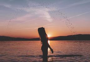 siluetas de hermosa modelo femenina al atardecer, amanecer en el fondo del mar, el sol, las nubes en colores rojo fuego, naranja foto