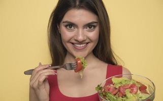 retrato de una chica juguetona feliz comiendo ensalada fresca de un bol foto