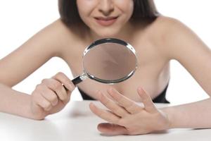 Woman looking her hand nails true magnifying glass. photo