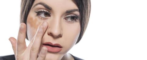 retrato de una mujer joven que aplica maquillaje líquido en la cara. aislado sobre fondo blanco foto