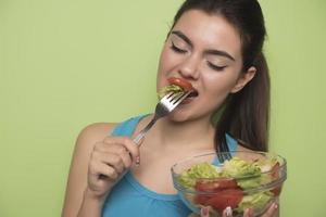 Portrait of a happy playful girl eating fresh salad from a bow photo