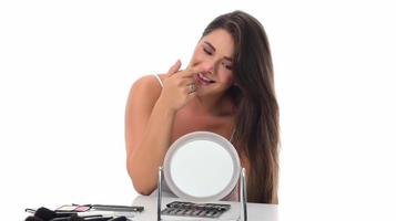 young woman checks her face skin in the mirror photo