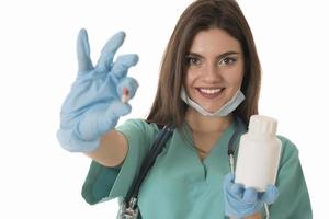 retrato de una doctora sonriente profesional con batas verdes sosteniendo una botella de píldora marrón atención médica foto