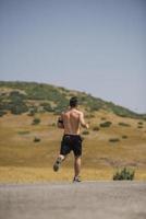 sporty man runner running on mountain plateau in summer photo