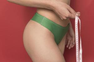 chica mide sus volúmenes con una cinta métrica. cuerpo sano y hermoso. cuerpo femenino, cintura delgada foto