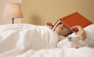 A young woman sleeping, covering her eyes with book photo