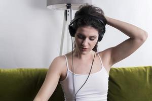 Cheerful young woman listening music in headphones in loft apartment photo