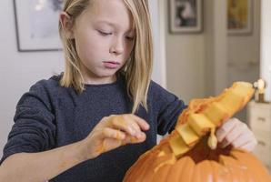 beautiful blond boy carving pumpkin with knife for Halloween. Halloween concept photo