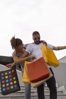 Portrait of cheerful Caucasian young couple man and woman holding many paper bags after shopping while walking and talking on street. Happy family couple with packages outdoor. Buying concept photo