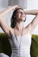 Una joven alegre escuchando música con auriculares en un apartamento tipo loft foto