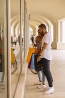 Portrait of cheerful Caucasian young couple man and woman holding many paper bags after shopping while walking and talking on street. Happy family couple with packages outdoor. Buying concept photo