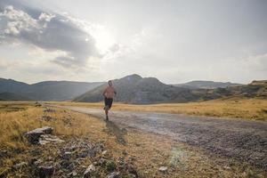 corredor de hombre deportivo corriendo en la meseta de la montaña en verano foto