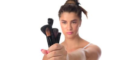 young girl posing with makeup brushes on a white background photo