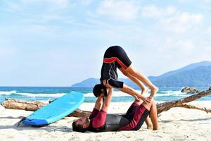 una pareja deportiva en forma practicando acro yoga con su pareja juntos. Una pareja deportiva en forma practicando yoga acrobático juntos en la playa foto