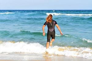 male coming out of the ocean after water surfing photo