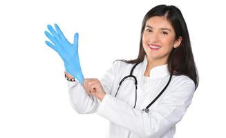 una joven doctora con estetoscopio poniendo guantes médicos, aislada de fondo blanco foto