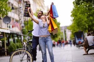 Portrait of cheerful Caucasian young couple man and woman holding many paper bags after shopping while walking and talking on street. Happy family couple with packages outdoor. Buying concept photo