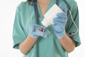 Portrait of professional female smiling doctor in green scrubs holding a brown pill bottle Medical Care photo