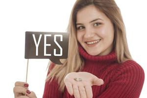 mujer sosteniendo un anillo de compromiso y un cartel diciendo que sí foto