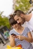 Portrait of cheerful Caucasian young couple man and woman holding many paper bags after shopping while walking and talking on street. Happy family couple with packages outdoor. Buying concept photo