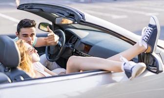 amigos divirtiéndose en un viaje en auto alrededor del mundo. pareja enamorada con los brazos arriba en un auto convertible. foto