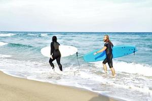 Surfers couple waiting for the high waves on beach - Sporty people with surf boards on the beach - Extreme sport and vacation concept photo