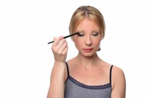 beautiful young smiling woman apply makeup with brush. isolated photo