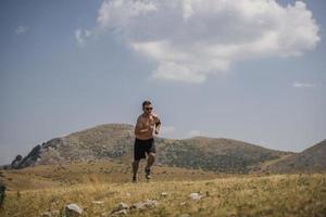 corredor de hombre deportivo corriendo en la meseta de la montaña en verano foto