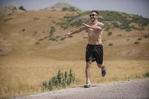 corredor de hombre deportivo corriendo en la meseta de la montaña en verano foto