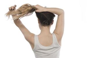 modelo femenino arreglando su cabello. mujer atando el cabello en un moño. foto