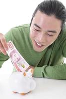 Asian man saving money in a piggy bank photo