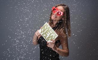 hermosa mujer celebrando el año nuevo con confeti y champán con cartel. aislado foto