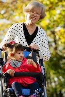 la abuela y su nieta autista disfrutan de las vacaciones juntas al aire libre, tumbadas en la hierba verde sobre una manta y sonriendo a la cámara. ocio estilo de vida familiar, felicidad y momentos. foto