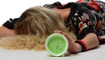 Happy young woman holding clock over isolated white background photo