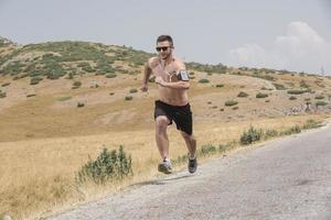 sporty man runner running on mountain plateau in summer photo