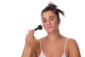 Portrait of a young woman applying make up on her face. Isolated on white background photo