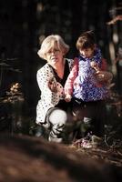 la abuela y su nieta autista disfrutan de las vacaciones juntas al aire libre, tumbadas en la hierba verde sobre una manta y sonriendo a la cámara. ocio estilo de vida familiar, felicidad y momentos. foto