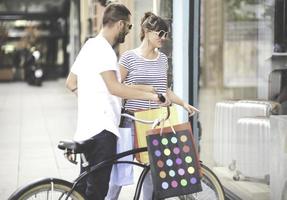 Portrait of cheerful Caucasian young couple man and woman holding many paper bags after shopping while walking and talking on street. Happy family couple with packages outdoor. Buying concept photo