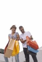 Portrait of cheerful Caucasian young couple man and woman holding many paper bags after shopping while walking and talking on street. Happy family couple with packages outdoor. Buying concept photo