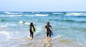 pareja de surfistas esperando las olas altas en la playa - deportistas con tablas de surf en la playa - deporte extremo y concepto de vacaciones foto