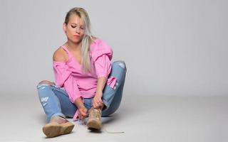 Portrait of beautiful young woman in cute pink shirt and blue jeans posing in studio. Concept of beauty, emotions, facial expression, lifestyle, fashion, youth culture photo