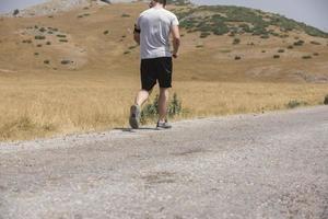 corredor de hombre deportivo corriendo en la meseta de la montaña en verano foto